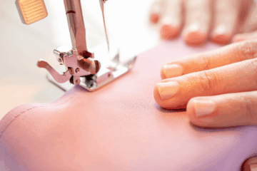 2 hands on pink fabric on sewing machine